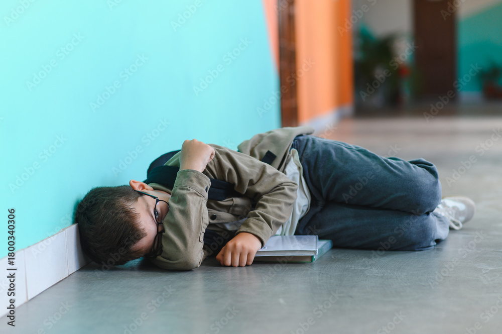 Fototapeta premium Schoolboy crying on floor after bullying incident at school