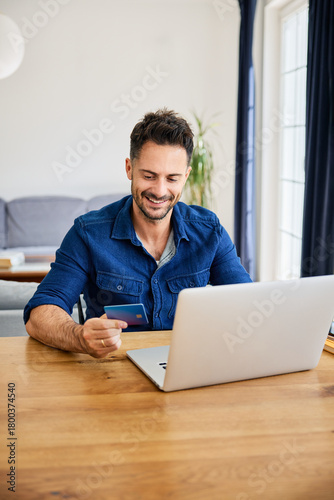 Man buying online paying with credit card using laptop at home