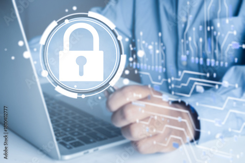 Businessman using laptop to analyze cybersecurity. IT specialist inspecting data protection and network security with virtual padlock icon and circuit board.