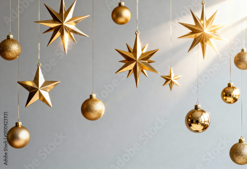 Golden Christmas ornaments hanging on a gray background. Festive stars and baubles for holiday decoration. Winter celebration concept with copy space