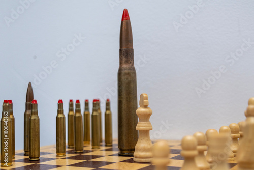 A tall bullet is surrounded by smaller bullets and chess pieces, creating a symbolic scene of hierarchy, strategy, and controlled tension. The composition highlights structure and contrast.