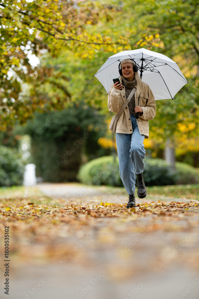 Obraz premium Young woman walking in park listening to music