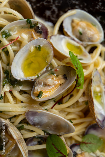 Spaghetti entangled with tender clams and fresh herbs is drizzled with olive oil, showcasing a delightful plate perfect for a cozy evening meal
