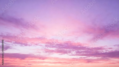 A serene sky at sunset with soft pink and purple hues blending across scattered clouds.