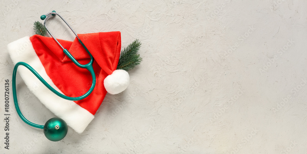 Obraz premium Stethoscope with Christmas tree branches and Santa hat on light background