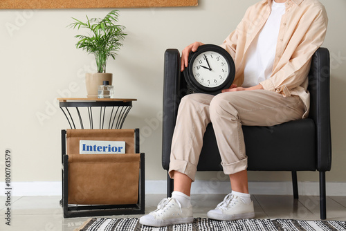 Young woman with clock sitt...