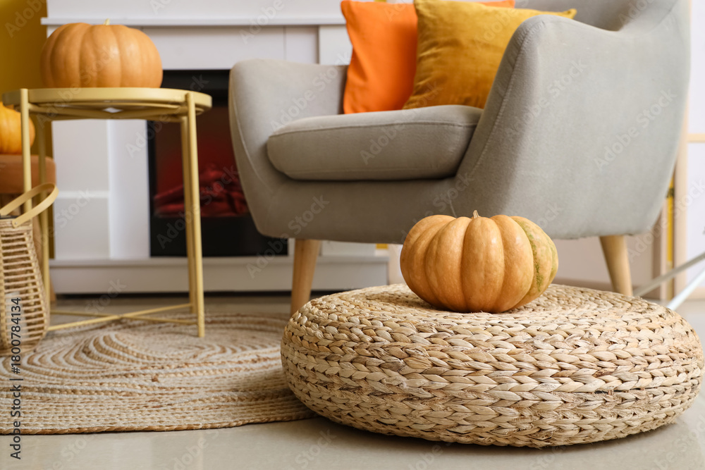 Naklejka premium Pumpkin on rattan pouf in living room, closeup