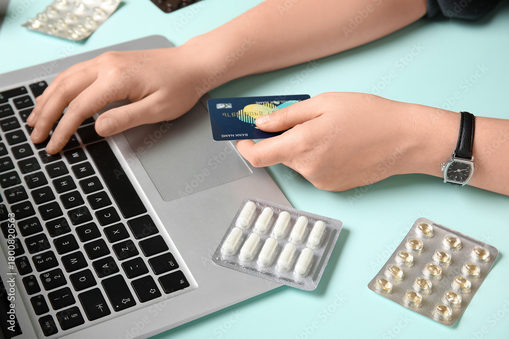 Obraz premium Female hands with modern laptop, credit card and pills on color background, closeup