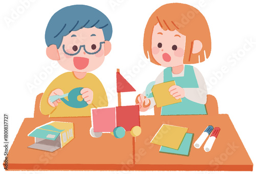 机に座って一緒に工作する小学生の男の子と女の子