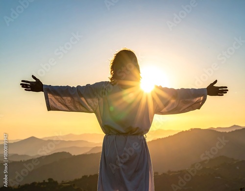 A person with outstretched arms stands against a stunning sunrise, silhouette against the bright sun with cascading light over mountain ranges