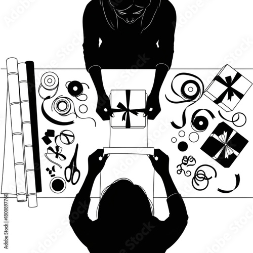 Top-down silhouette view of two people wrapping gifts together on a table.