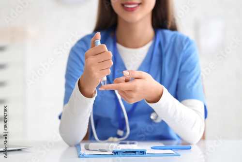 Female doctor with lancet pen giving online consultation in clinic, closeup