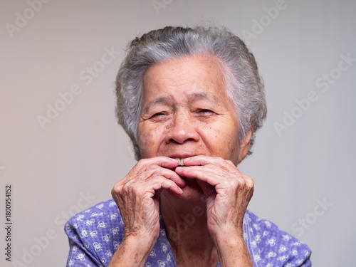 Elderly woman inserting denture with both hands.