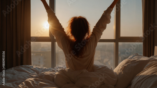 Young woman stretches in bed, enjoying morning sun streaming through window, radiating sense of peace and renewal