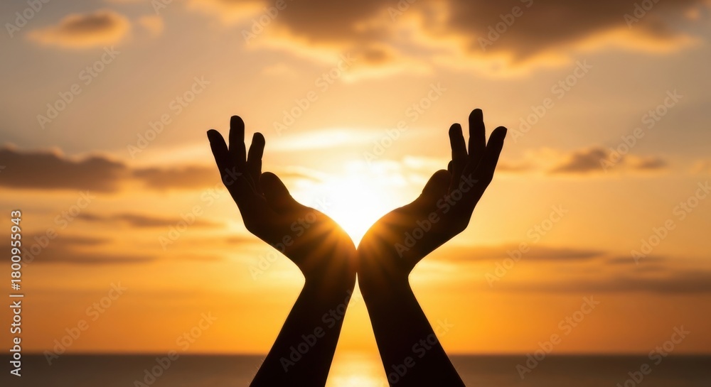 Fototapeta premium Silhouette of hands cupped together against a vibrant sunset, symbolizing hope and spirituality