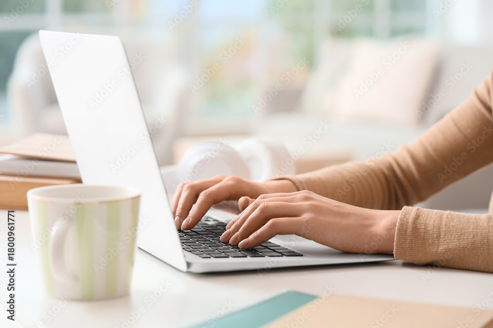 Fototapeta premium Female hands using laptop to search online on table at home, closeup