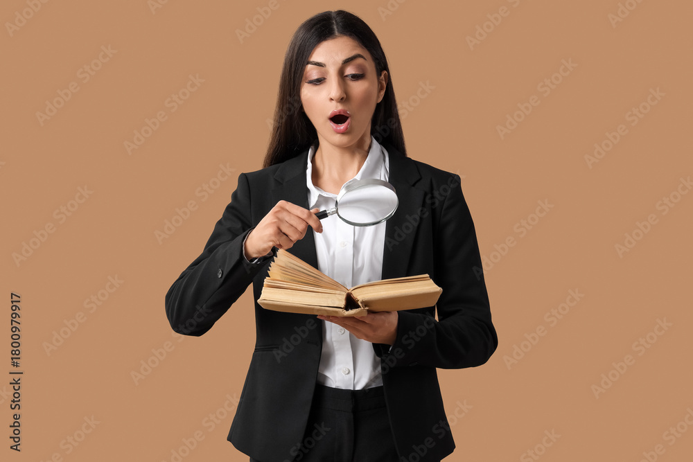 Fototapeta premium Shocked businesswoman with magnifier and book on beige background. Search concept