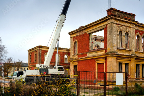 Restoration work on an old brick building with a crane and construction equipment at a historic site under renovation.