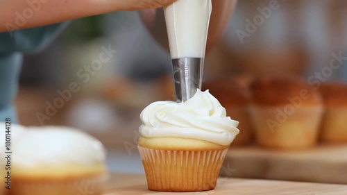 A person decorating a cupcake with frosting, with other cupcakes Stock Video