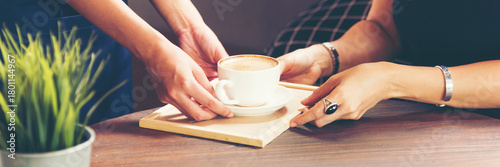 Fototapet Banner Close up woman hands holding disposable paper coffee cup drinking outdoor in green park bokeh blurred background