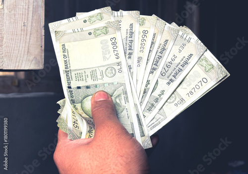 Closeup focused photo of a man showing money in his hand. A person counting cash or money in his hand. A boy having indian rupees or indian currency money in hand. an employee showing his money.