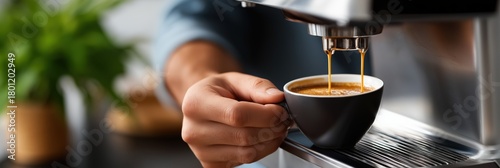 Close-up of hand brewing fresh espresso in black cup with machine