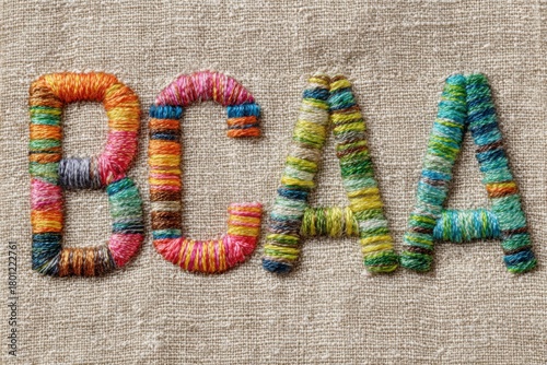 Colorful bcaa letters displayed on tan linen background embellished with embroidery.Sports nutrition. Vitamin C. Healthy eating. Sport.