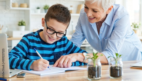 Grandmother helping her grandson with homework at the kitchen table with laptop and plants
