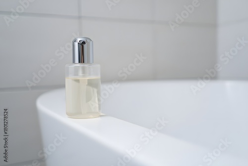 Clear glass dropper bottle of serum on the edge of a white bathtub