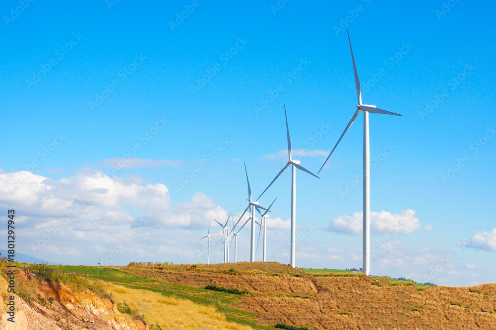 Fototapeta premium Wind Turbine Farm on a Hill Under a Bright Blue Sky