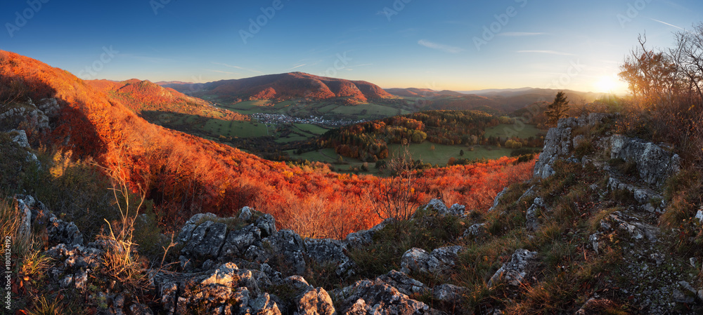 Naklejka premium Mountains at sunset. Landscape with hills orange trees and grass in fall, colorful sky with golden sunbeams. Seasonal natural scene
