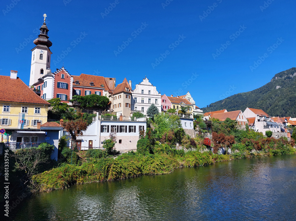 Obraz premium old buildings and green embankment of town Frohnleiten under blue sky at sunny day. Austria