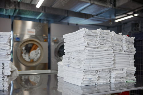 Canvastavla A stack of clean towels is on a table in front of a washing machine