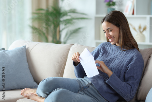 Happy woman in blue opening envelope at home
