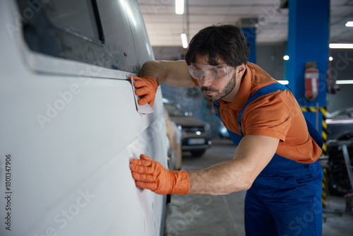 Fotografie An auto body technician is meticulously inspecting a car panel in the repair sho