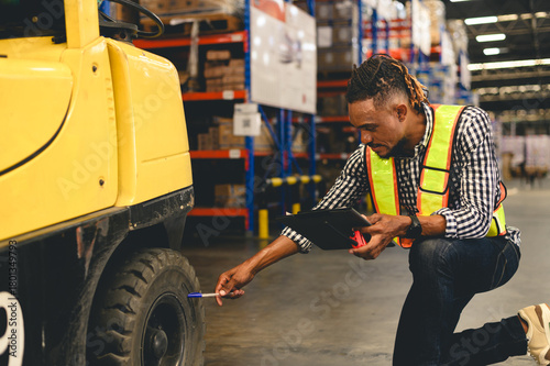 Warehouse worker wearing a safety vest checking a forklift tire with a clipboard and paper, representing safety inspection, maintenance, and quality control in industrial and logistics operations