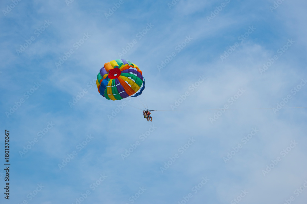 Fototapeta premium Parasailing couple flying high in blue sky enjoying adventure