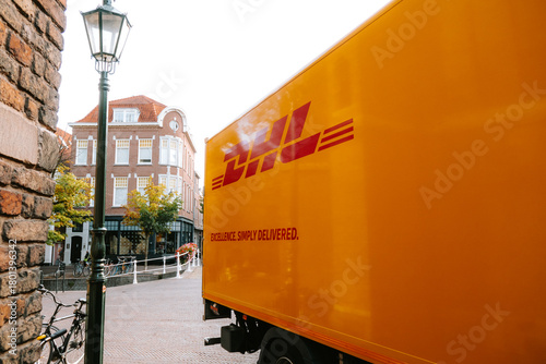 Fototapeta Naklejka Na Ścianę i Meble -  DHL small delivery truck parked on a street corner in a European city. Wide angle view of the rear of the truck, no people