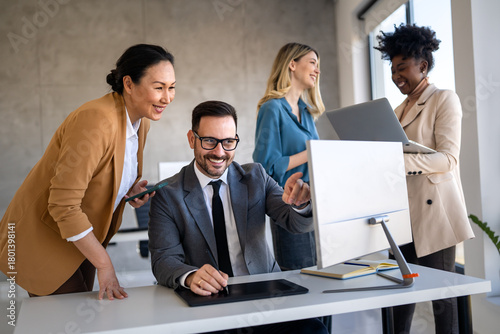 Happy multiethnic businesspeople laughing while collaborating on a new project in an office.