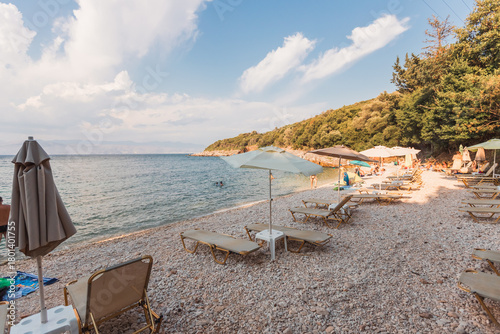Obraz na płótnie Beach with umbrellas and swimmers by green hillside