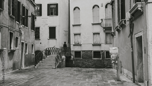 Fototapeta Naklejka Na Ścianę i Meble -  A person dressed in a vintage outfit crossing a bridge in Venice