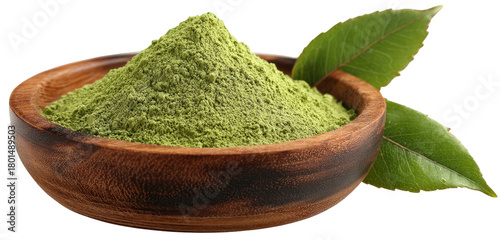 A wooden bowl overflowing with vibrant green powder, two leaves beside it