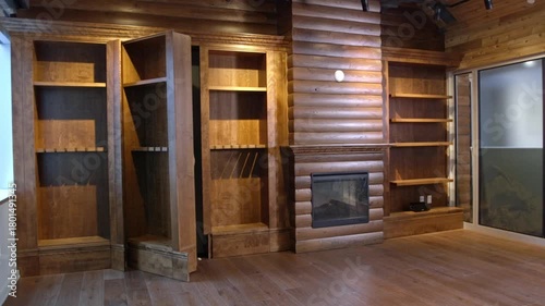 A hidden doorway in a wall of bookshelves opens to reveal a concealed room. From within a man comes out examining the door with great interest and wonderment