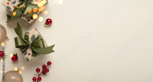 Merry Christmas and Happy Holidays greeting card, frame, banner. New Year. Christmas ornaments and gifts, presents on light beige background top view. Winter xmas holiday festive theme.