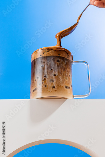 Milky coffee action shot with spoon and glass mug