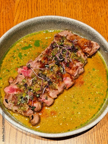 Juicy grilled steak with herbs and sauce served in bowl. Hugh-quality gourmet meal photo ideal for restaurant menus, advertising, or premium food branding. 
