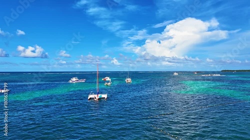 Caribbean seascape with boats at a Dominican beach. Aerial view of floating boats on a blue sea on a sunny morning. Aerial drone view of the beach and blue sea. Summer vacation and holidays.