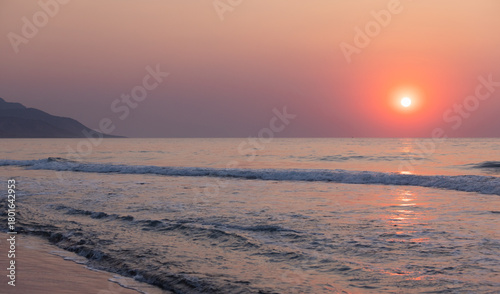 Fototapeta Naklejka Na Ścianę i Meble -  A tranquil sunset paints the sea with warm orange and pink hues