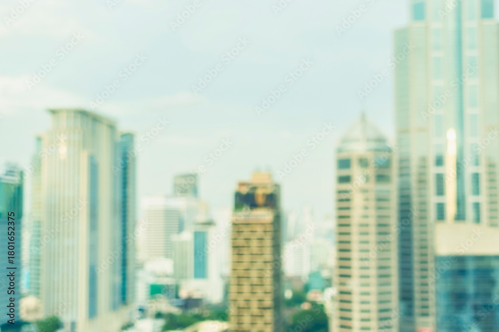 Obraz premium Blurred modern city skyline with towering skyscrapers under a bright sky