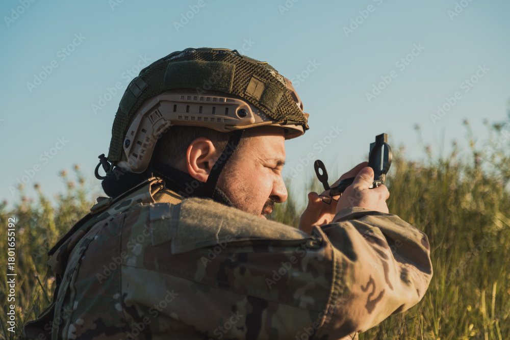 Fototapeta premium Soldier Looking At The Compass While In A Field